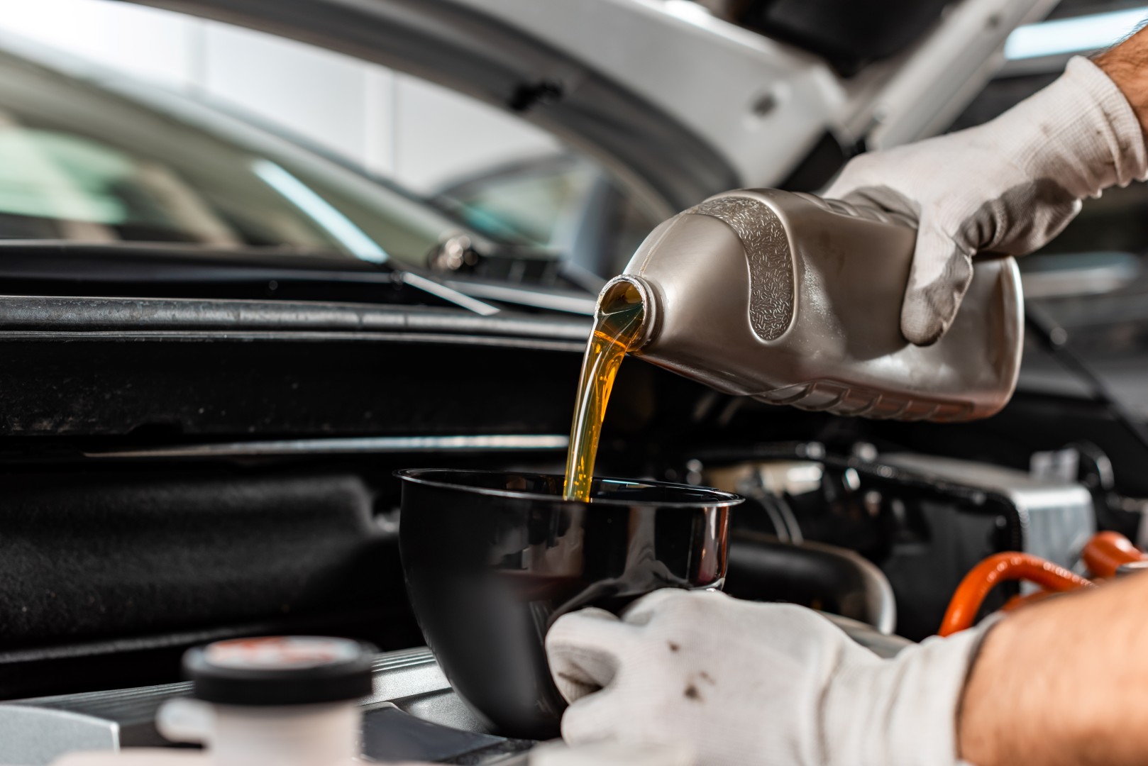 partial view of mechanic pouring motor oil at car engine