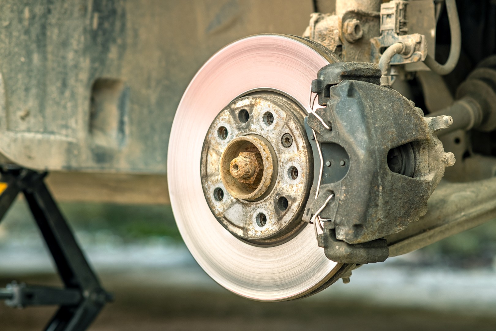 Closeup of braking disc of the vehicle with brake caliper for repair in process of new tire replacement. Car brake repairing in garage.